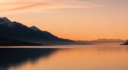 Snow capped mountain range over a calm lake. Serene nature landscape for wellness and meditation. Golden hour sunrise with water reflection. Outdoor travel and exploration concept