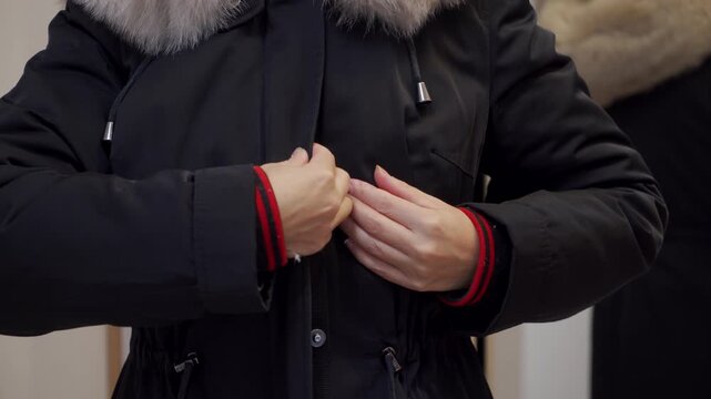 Quick Task: Woman Snaps Buttons on Black Parka Shut for Warmth and Departure