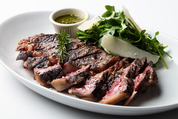 Plate of sliced steak with salad and chimichurri sauce 