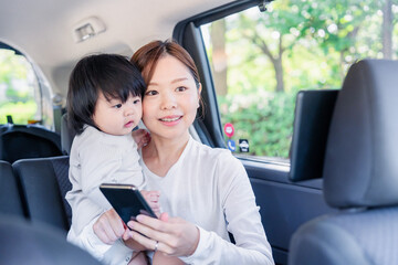 小さい子供と一緒にタクシーに乗るお母さん