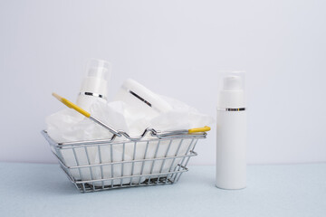 Miniature basket filled with white, unlabeled cosmetic bottles on a minimalist background. Beauty...
