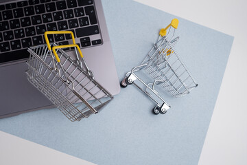 Miniature metal shopping basket placed on a laptop keyboard with copy space. E-Commerce and online shopping concept