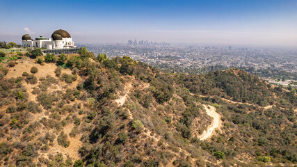 Panoramic view of Griffith Observatory overlooking Los Angeles skyline. Rolling hills, hiking trail, clear blue sky, urban landscape, California scenery, majestic dome structure, perfect day shot.