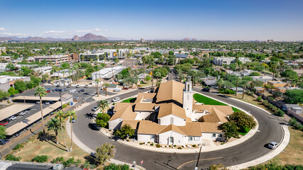 Aerial view of a historic church in Phoenix, Arizona. Sunny day, palm trees, suburban landscape, architectural detail. Perfect for travel, community, faith imagery.