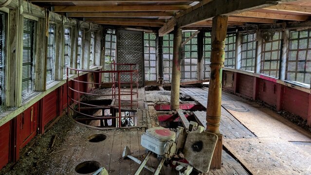 Inside decaying abandoned ship. Old-fashioned pirate boat interior with boarded up windows, rusty railings, damaged wooden hole filled floor. Dust, dirt, debris and decay in an eerie atmosphere. - Powered by Adobe