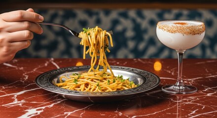 Fine dining with Italian pasta and a craft cocktail. Person enjoying a gourmet spaghetti meal. Elegant restaurant setting with a luxurious marble tabletop. Food and drink pairing concept