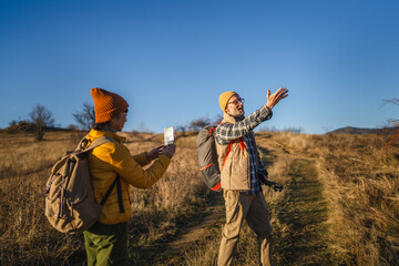 Senior couple hiking, navigating trail using smart phone map