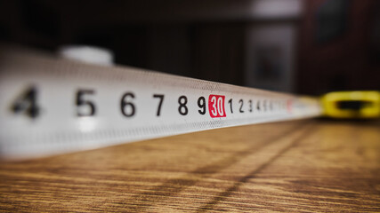 Measuring tape laid on wooden surface in close up