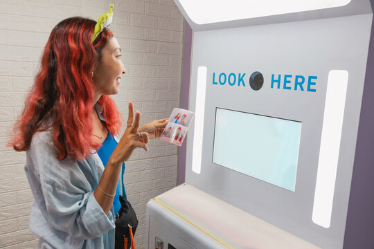 Tourist making playful faces and fun hand gestures while capturing memories in a vibrant photo booth, enjoying a lighthearted moment indoors