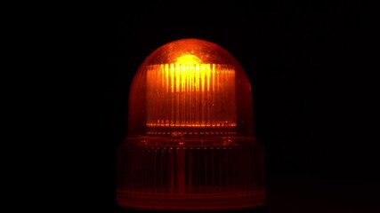 Close up of a flashing caution light on black background - Powered by Adobe