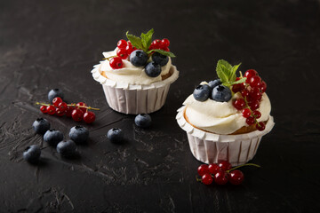 Delicious vanilla cupcakes decorated with mascarpone cream and berries (blueberries, currants, mint)