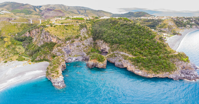 Aerial view of Arcomagno coast in Calabria Italy showing turquoise sea meeting rugged cliffs and hidden caves surrounded by lush Mediterranean vegetation symbolizing untouched natural beauty