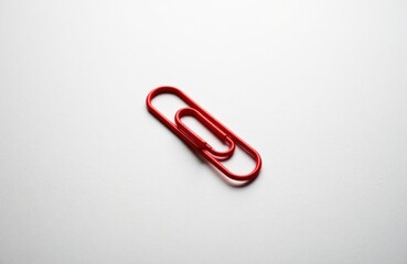 Obraz premium A red paperclip lies on a plain white surface creating a simple minimalist scene