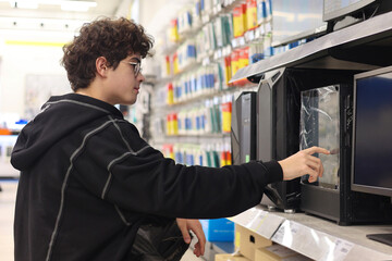 Teenager Choosing a Desktop PC in Electronics Store – Young Customer Selecting Computer Tower for Gaming or Study, Tech Shopping. digital lifestyle, and making purchase decisions among Gen Z. © Светлана Мищенко