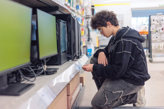 Teenager Choosing a Desktop PC in Electronics Store – Young Customer Selecting Computer Tower for Gaming or Study, Tech Shopping. digital lifestyle, and making purchase decisions among Gen Z.