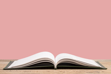 open book. Composition with hardback books, fanned pages on wooden deck table and pink background. Books stacking. Back to school. Copy Space. Education background.