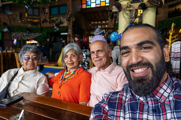 Colombian multigenerational family taking selfie at festive restaurant table with Wayuu accessories in Guarne, Antioquia