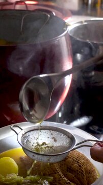 Slow motion. The cook pouring broth into the stew through a strainer.