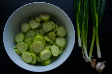 A white plate filled with sliced cucumber, green onions, and garlic