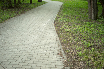 A path in the park. Tile driveway. Empty area.