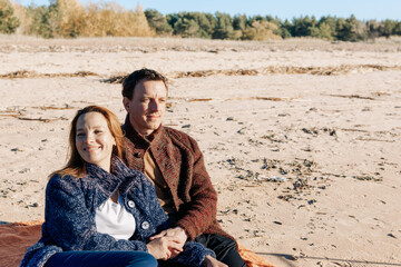 Loving couple walks on beach along sea on sunny autumn day. Weekend and lifestyle concept. High quality photo
