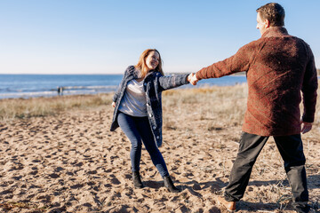 Loving couple walks on beach along sea on sunny autumn day. Weekend and lifestyle concept. High quality photo