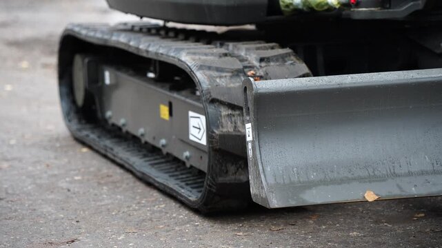 Close up of rubber crawler track and metal blade on construction machine showing industrial power, modern engineering precision, and durable mechanical structure details
