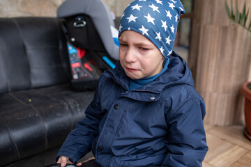 Upset young boy crying loudly with tears running down his face, wearing a star-patterned hat and a navy blue jacket outdoors © Татьяна Швец
