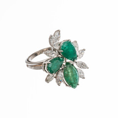 platinum ring with two pear-cut emeralds and one marquise-cut emerald surrounded by nine diamond navettes, isolated on white background