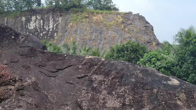 randomly split rock formation located in a rural Kerala village, surrounded by greenery and natural landscape