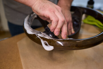 Thorough leather surface purification, Intensive scrubbing of vehicle steering wheel, Applying focused scrubbing technique with bristles to lift grime from steering wheel