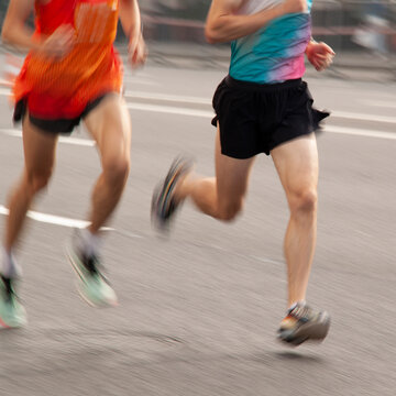 Two men in sportswear are running quickly along a city street