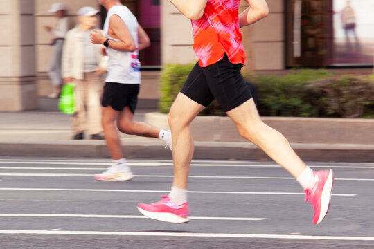 two runners in sportswear rush along a city street