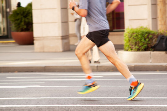 runner in sportswear runs along a city street