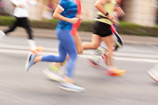 Several runners, men and women, jogging along a city street