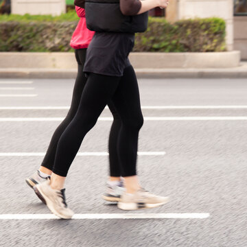 Two athletic women jog leisurely through a summer city