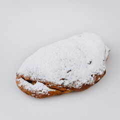 Traditional Christmas stollen loaf with powdered sugar on white background, holiday dessert