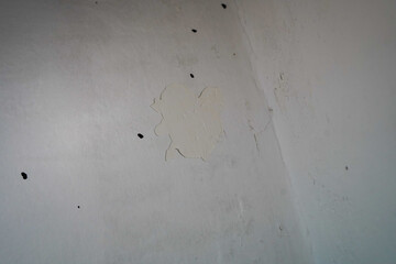 Peeling paint and wall damage in a dark interior corner, sign of moisture and neglect