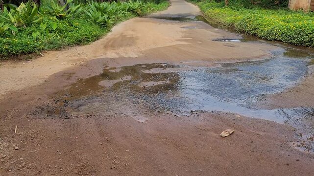 Clean water flowing and wasting over a village road because of a broken pipe, highlighting rural infrastructure and water conservation issues