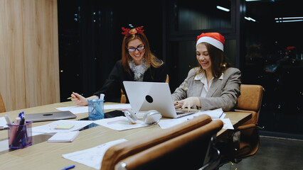 Business women collaborating in a modern office while preparing for Christmas celebrations in the...