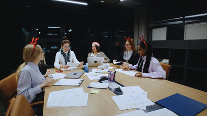 Business women collaborating in a festive office environment in the evening before Christmas...