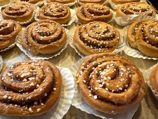 Freshly baked Swedish cinnamon buns, kanelbullar, with pearl sugar topping traditional fika pastry on baking tray