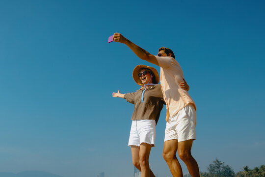 Happy caucasian adult couple taking selfie on a sunny beach day - Powered by Adobe