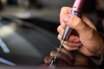 Glass repair process, Detailed shot of resin filling windshield flaw, Focuses on craftsman...