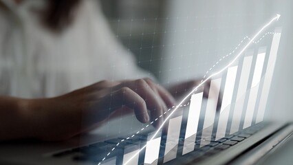 A close-up of hands typing on a laptop, complemented by a graphic of a rising business graph, symbolizing growth, success, and the modern work environment. Copula