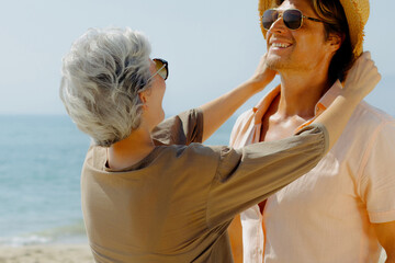 Elderly caucasian couple enjoying a beach day with smiles and sun hat