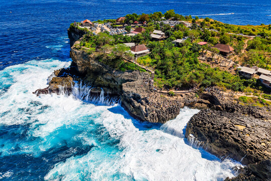 Aerial view of powerful ocean waves crashing against rocky cliffs on Nusa Penida, Bali