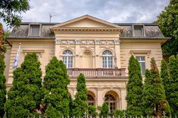 Budapest, Hungary – July 27, 2025: Colorful residential buildings with ornate balconies and street-level shops in downtown Pest, capturing the city’s architectural charm and everyday urban life.
