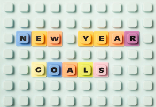 The phrase NEW YEAR GOALS spelled out on a light blue studded board using colorful plastic letter tiles, symbolizing planning, resolutions, and future aspirations.