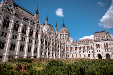 Fototapeta premium Budapest, Hungary - July 27, 2025: The Hungarian Parliament Building viewed from its garden side, showcasing its magnificent Neo-Gothic architecture with detailed spires and ornate stonework.